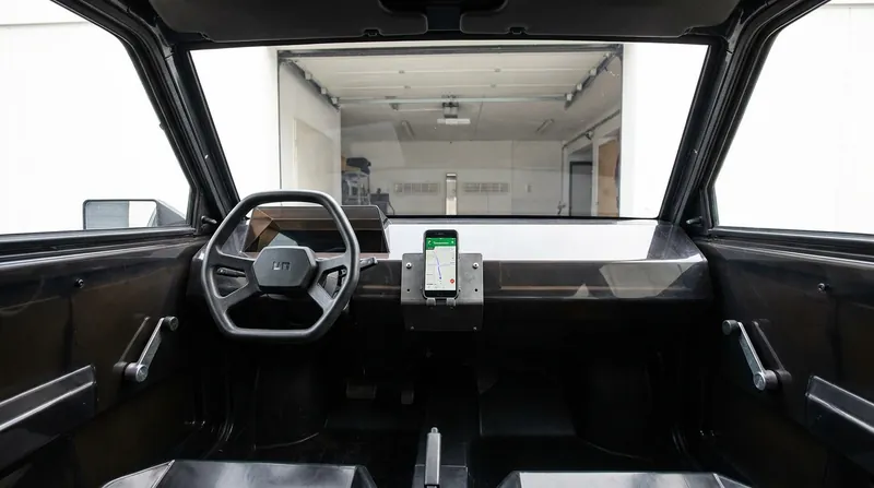 The interior strips away screens and power windows, relying on the driver's smartphone for media and navigation.