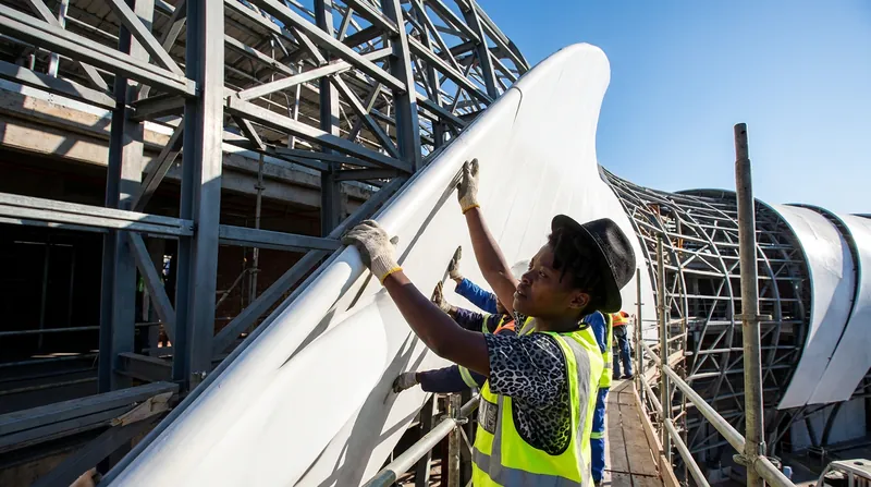 The building's undulating exterior is composed of over 1,500 unique, robotically fabricated fiberglass panels.