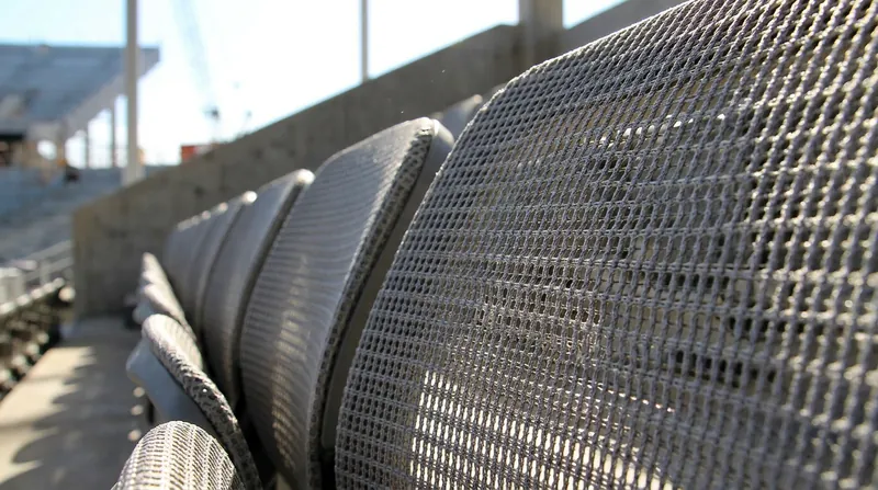 Breathable mesh seating is replacing traditional solid plastic to maximize airflow and lower surface temperatures for fans.