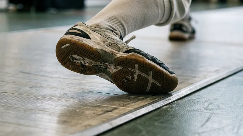 Modern fencing footwear is increasingly engineered with targeted heel foams to dissipate the violent impact of the lunge strike.