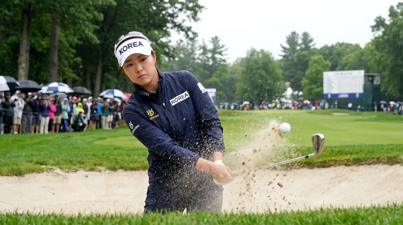 Hyo Joo Kim battles out of a fairway bunker on the 18th hole after a costly slip in the rough.