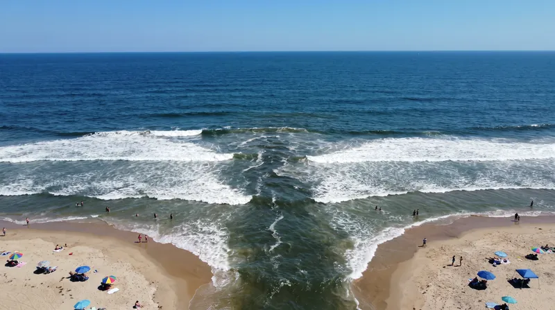 Rip currents often appear as darker, calmer channels of water flowing back out to sea.