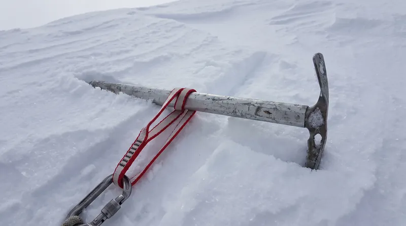 A buried ice axe, known as a T-trench or deadman anchor, provides the secure point required to build the hauling system.