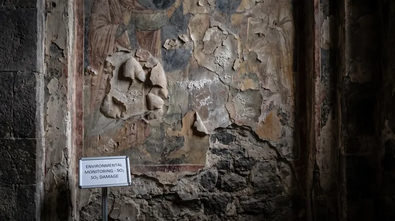 Industrial sulfur dioxide converts the stable calcium carbonate into gypsum, causing the plaster to expand and crumble.