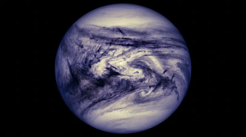 A false-color ultraviolet image of Venus showing dark, sweeping streaks across its pale cloud cover.