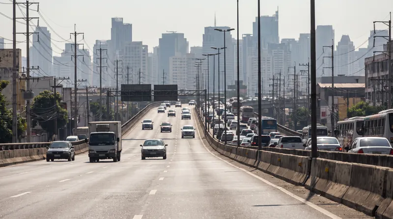 A wide-angle view of a major urban highway shimmering with severe heat haze against a city skyline.