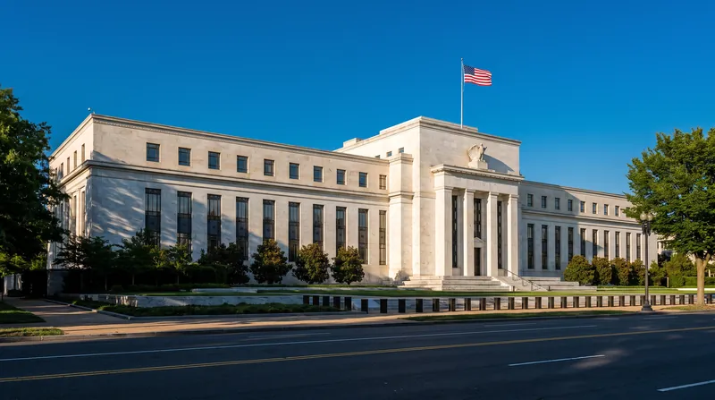 The exterior of the Federal Reserve building in Washington D.C. during daytime with American flags flying.