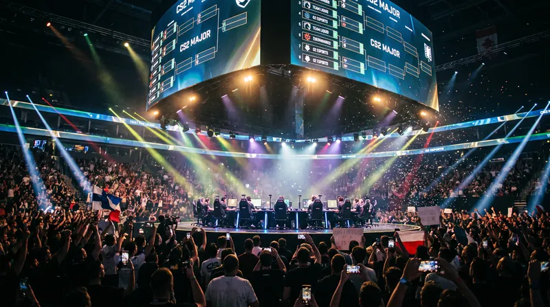 A brightly lit esports arena stage with two teams of five players competing at gaming desks.