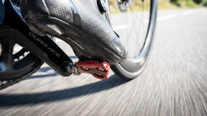 Close-up of a cyclist's stiff carbon-soled shoe securely clipped into a modern road bike pedal.