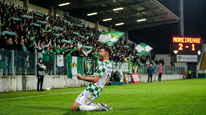 A Moreirense soccer player in a green and white kit celebrates a goal on the pitch.