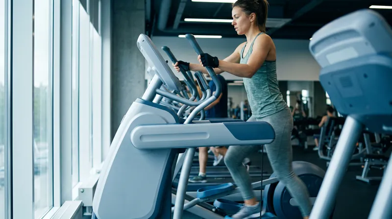 An athlete working out on an elliptical trainer in a modern gym setting.