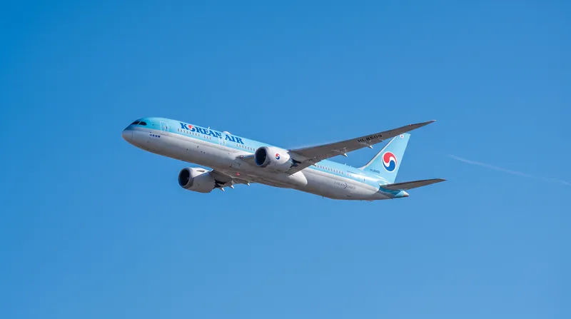 A Korean Air Boeing passenger jet flying in a clear sky, displaying the airline's signature blue livery.