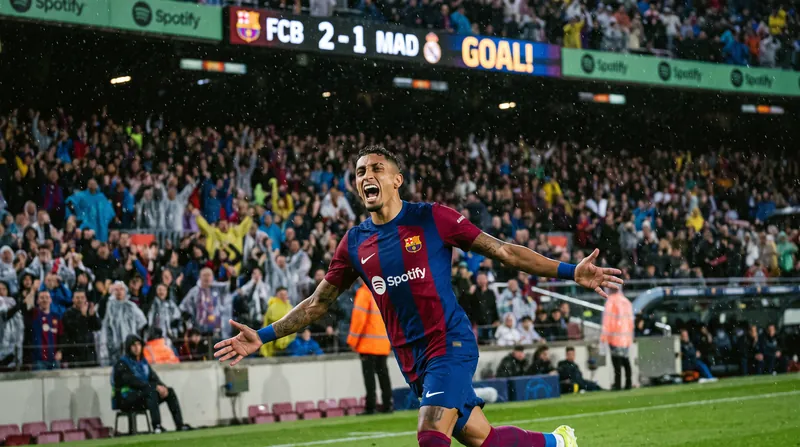 Barcelona forward Raphinha celebrates scoring a goal in the rain at Camp Nou.
