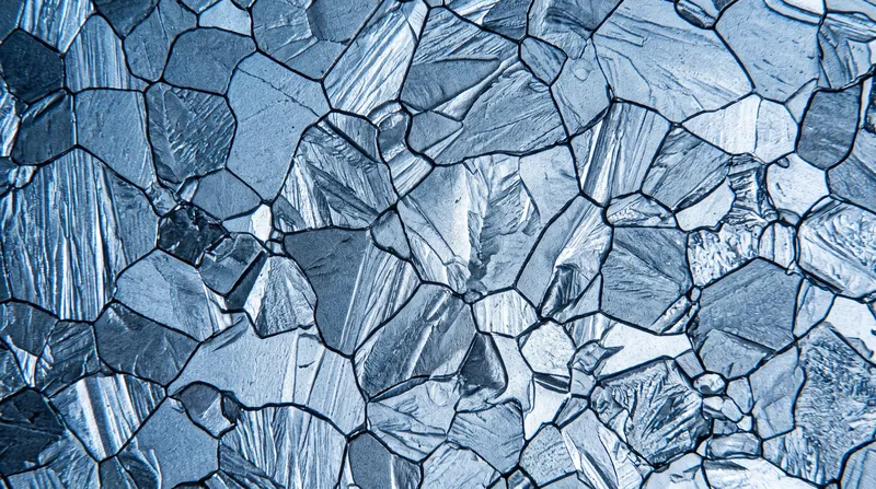 A microscopic view showing the interlocking geometric crystal grains and boundaries on the surface of a metal.