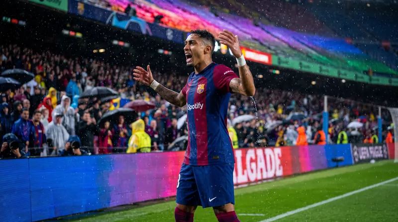 Raphinha of FC Barcelona celebrates scoring a goal in the rain at Camp Nou stadium.