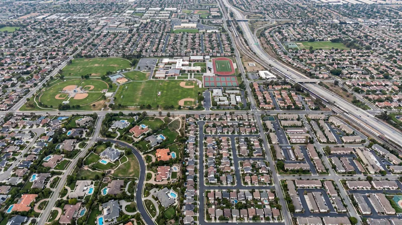 Aerial photograph showing adjacent suburban neighborhoods with different housing densities and infrastructure, illustrating municipal boundaries.