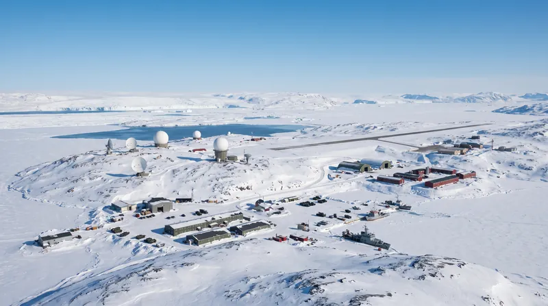 Aerial view of military radar installations and buildings surrounded by snow and ice in Greenland.