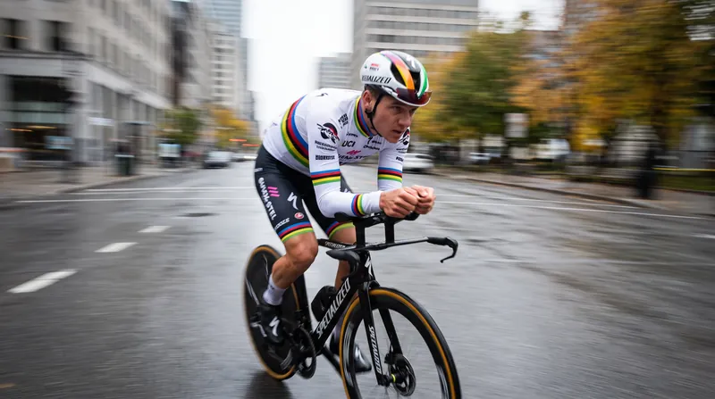 Remco Evenepoel wearing the rainbow jersey rides an aerodynamic time trial bicycle at high speed.