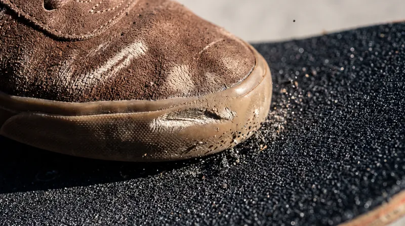 Kinetic friction between the shoe and the grip tape is what physically pulls the unattached board into the air.