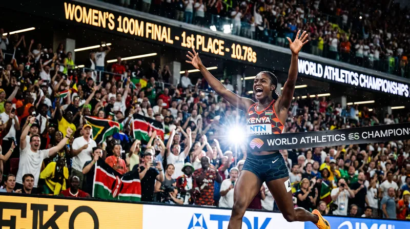 Female sprinter crossing the finish line at a packed stadium under bright lights.