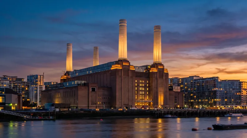 Exterior view of the historic Battersea Power Station in London at dusk, featuring its four iconic white chimneys.