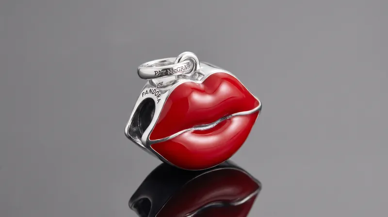 The collection features charms inspired by McGrath's signature beauty looks, including bold red lips.