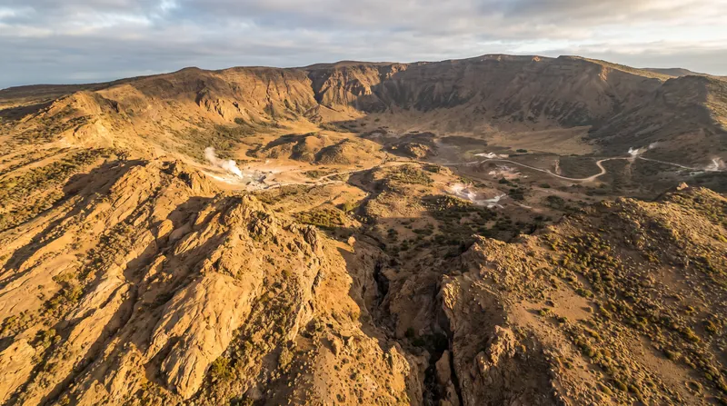 A vast, rugged volcanic caldera stretches across the landscape, showing the massive depression left by a super-eruption.