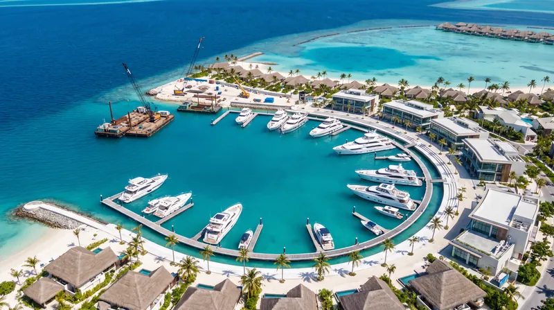 Aerial rendering of a luxury marina and waterfront promenade in the Maldives with docked superyachts.