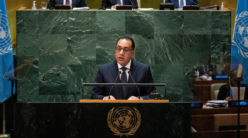 Egyptian Prime Minister Mostafa Madbouly speaking at a podium with the green marble background of the UN General Assembly.