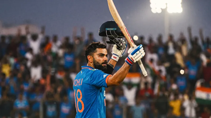 Virat Kohli in his blue India ODI kit, holding his bat up to acknowledge the crowd.