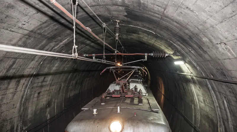 High-voltage AC systems require significant vertical clearance to prevent electrical arcing, complicating tunnel upgrades.