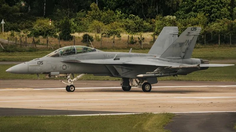 A US Navy fighter jet parked on the flight deck of an aircraft carrier at sea.