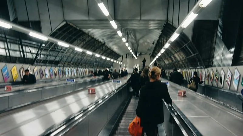 A dense crowd of commuters standing side-by-side on a long escalator in a transit station.