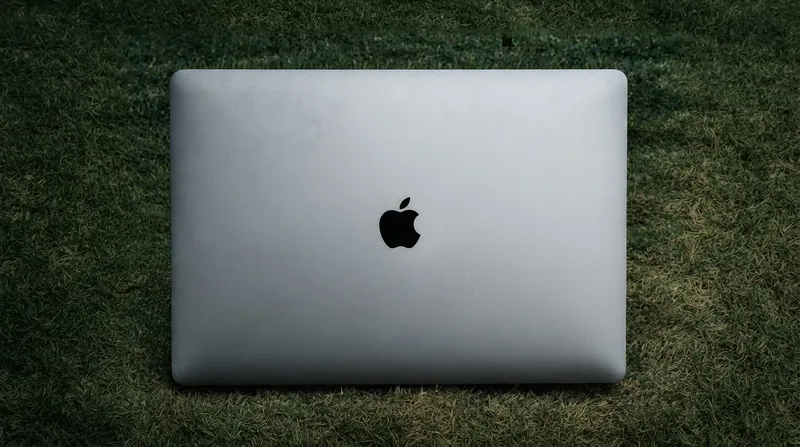 A modern MacBook Pro displaying a system privacy warning dialog on its screen, sitting on a wooden desk.