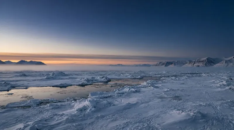 Dark, open Arctic ocean water surrounded by fragmented sea ice, with a thick layer of fog sitting heavily on the surface.
