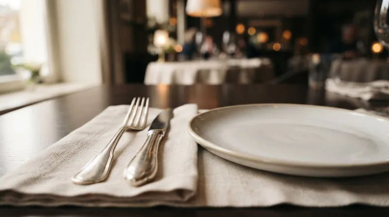 A close-up of a heavy stainless steel fork resting next to a plated meal in a restaurant.