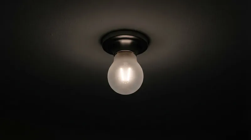 A modern LED bulb glowing faintly in a dark room, exposing the internal yellow diode chips.
