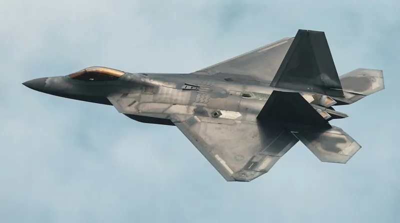 A U.S. Air Force F-22 Raptor stealth fighter flying in close formation with a jet-powered drone.