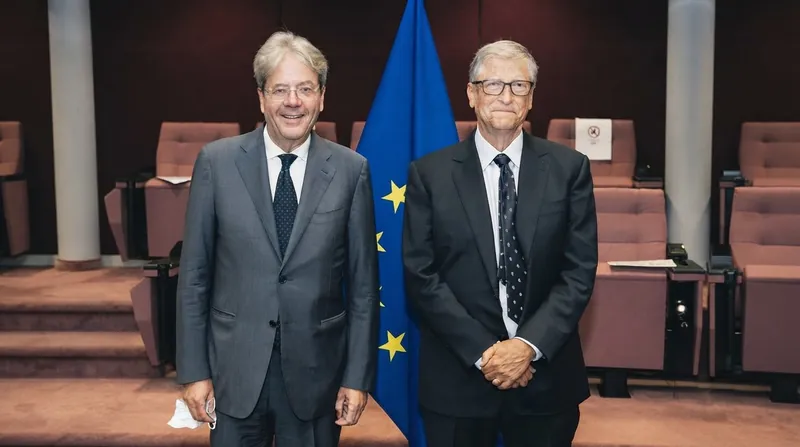 Bill Gates speaking at a podium in a corporate setting.