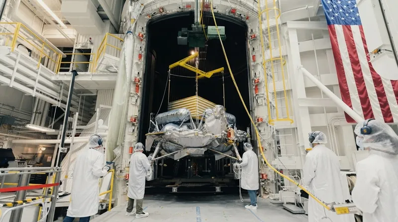 A compact four-wheeled lunar rover with solar panels driving across the grey surface of the Moon.
