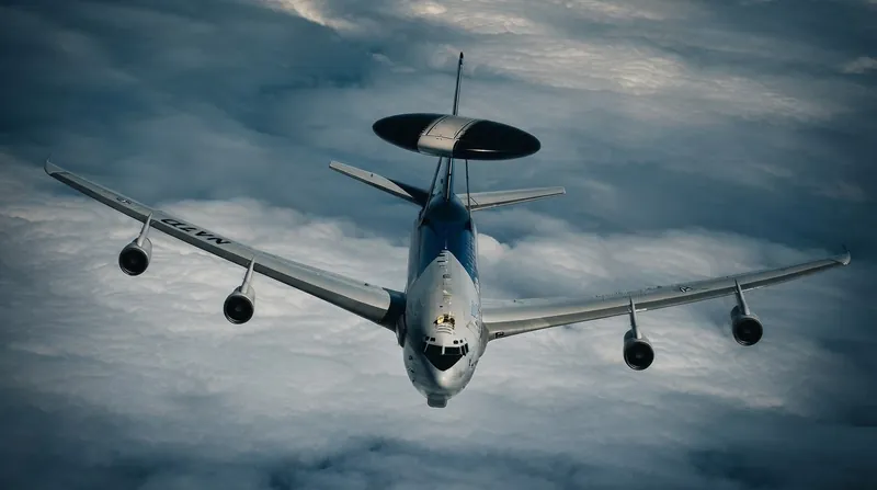 A NATO AWACS surveillance aircraft parked on a runway with ground crew conducting checks.