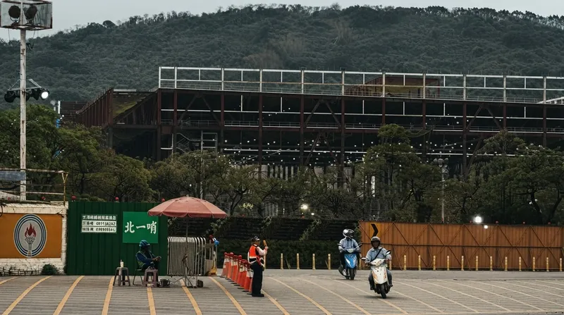 Heavy steel beams and construction cranes at a massive semiconductor fabrication plant site in Kaohsiung, Taiwan.