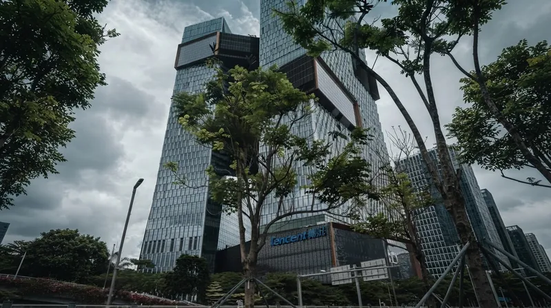 Modern glass skyscrapers of the Tencent corporate headquarters illuminated against the evening sky in Shenzhen.