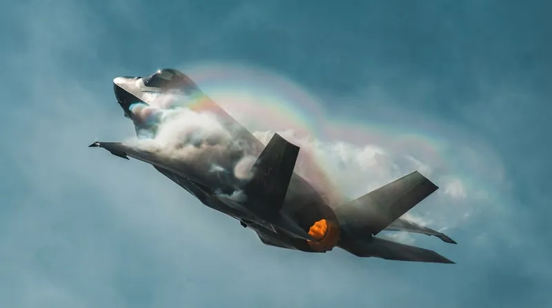 An F-35 Lightning II fighter jet parked on a military flight line with ground crew working nearby.