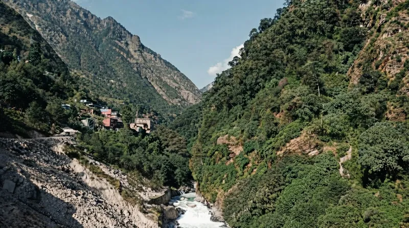 Collapsed infrastructure and thick mud covering a village next to a fast-flowing river in Nepal.