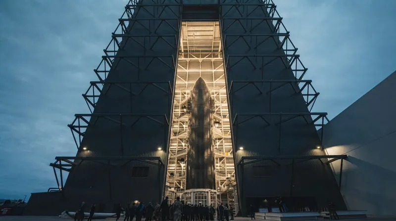 Industrial infrastructure at a SpaceX facility illuminated at dusk.