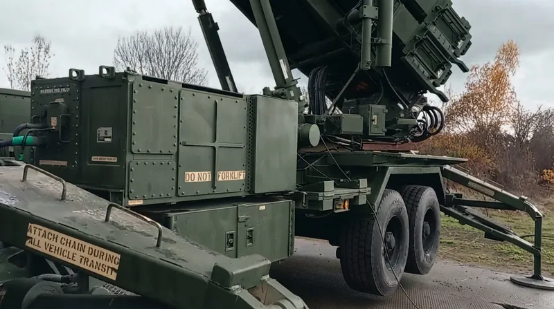 A Patriot air defense radar system deployed in a field under an overcast sky.