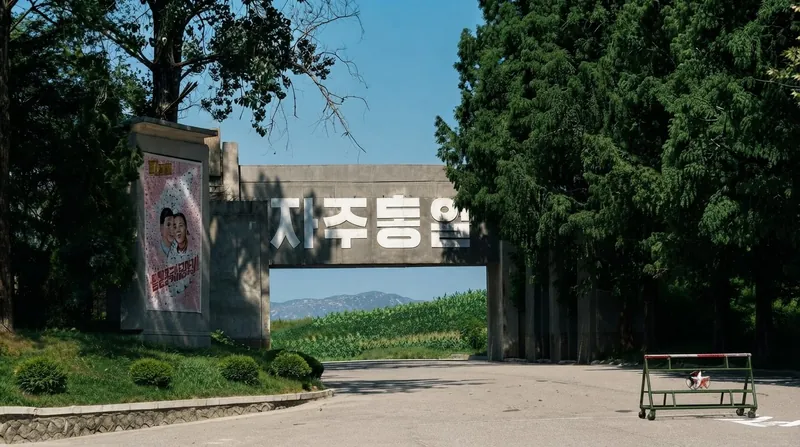 A view of the Korean Demilitarized Zone showing barbed wire fences and distant coastal terrain under overcast skies.