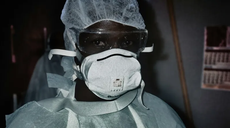 Medical workers wearing full yellow personal protective equipment walk through a rural treatment center.