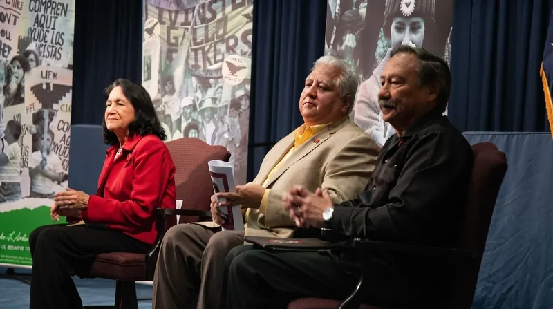 Black and white historical photograph of Dolores Huerta speaking passionately at a United Farm Workers rally.